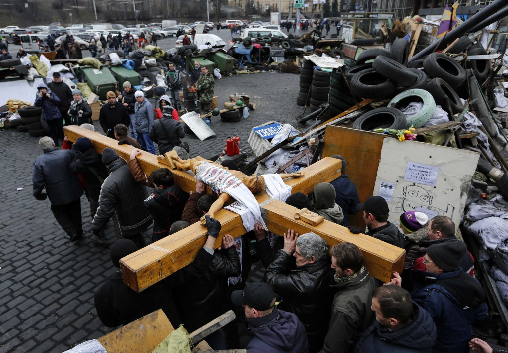 Mourners carry a large wooden crucifix past a barricade during a memorial procession in Independence Square in Kiev, Ukraine, Feb. 25. Dozens of protesters have been killed since November. PHOTO: CNS/Yannis Behrakisi, Reuters