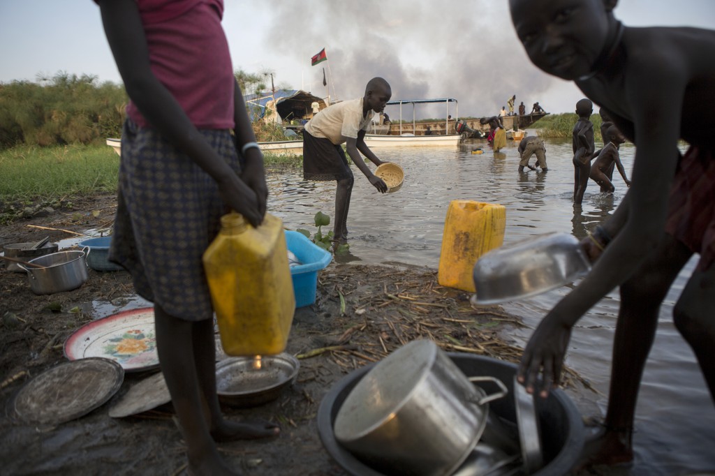 People collect water, wash dishes, do laundry and play on the banks of the Nile River, in Ahou, South Sudan. An estimated 716,100 people have been displaced in South Sudan with an additional 166,900 fleeing to neighboring countries as a result of conflict that erupted in mid-December. PHOTO: CNS/Sara Fajardo, Catholic Relief Services