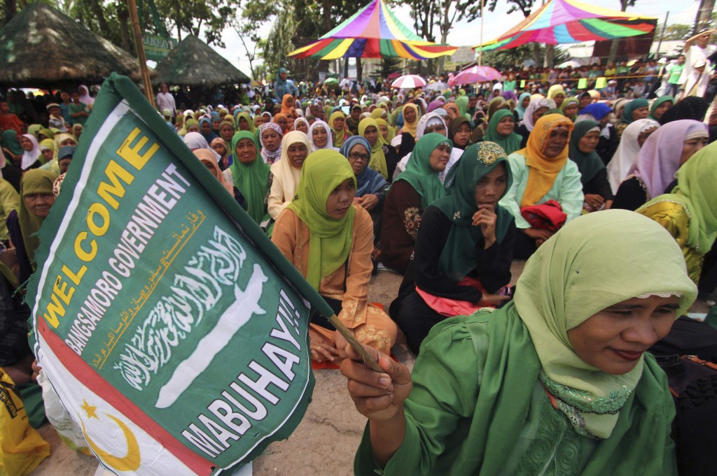 A Moro woman holds a flag of the Moro Islamic Liberation Front during a gathering in Pikit, Philippines, March 27. The Philippines and its largest Muslim rebel group signed a final peace pact, ending about 40 years of conflict that has killed more than 120,000 people in the country's South. PHOTO: CNS/Keith Bangcoco, Reuters