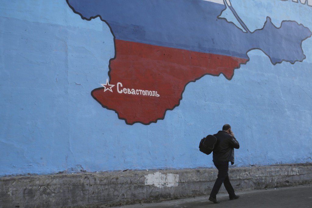 A man passes a mural showing a map of Crimea in the Russian national colors on a street in Moscow March 25. A Ukrainian Catholic priest from Crimea says he fled to Ukraine because Russian authorities are pressuring ethnic Ukrainians. PHOTO: CNS/Artur Bainozarov, Reuters