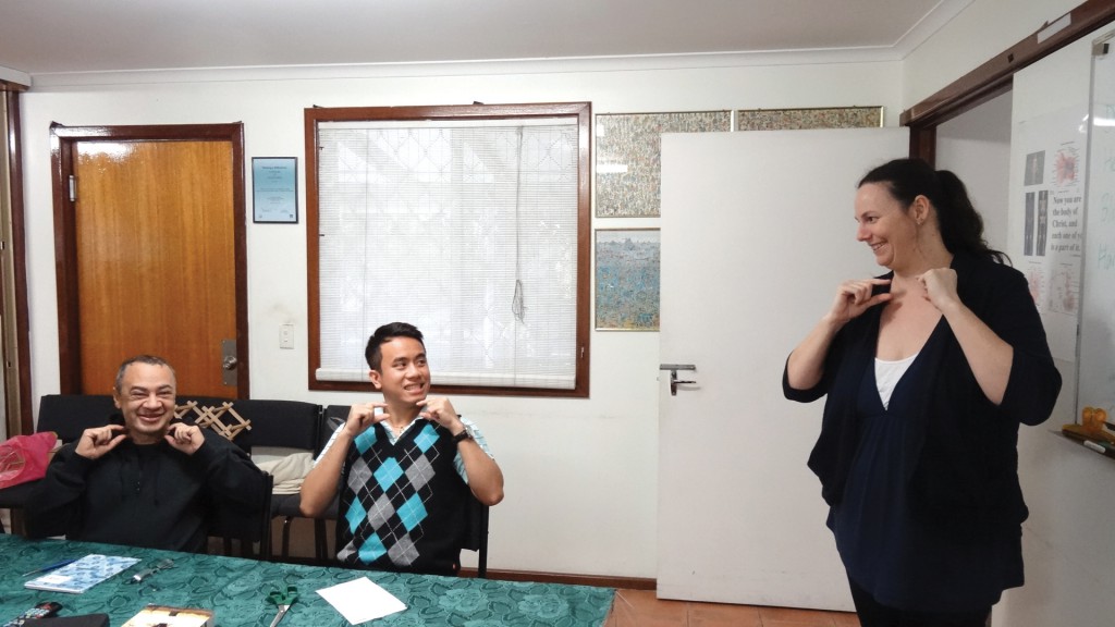Auslan teacher Emma Chevron shows seminarians Gerard Nemorin and Joseph Hoang the sign for “priest”.