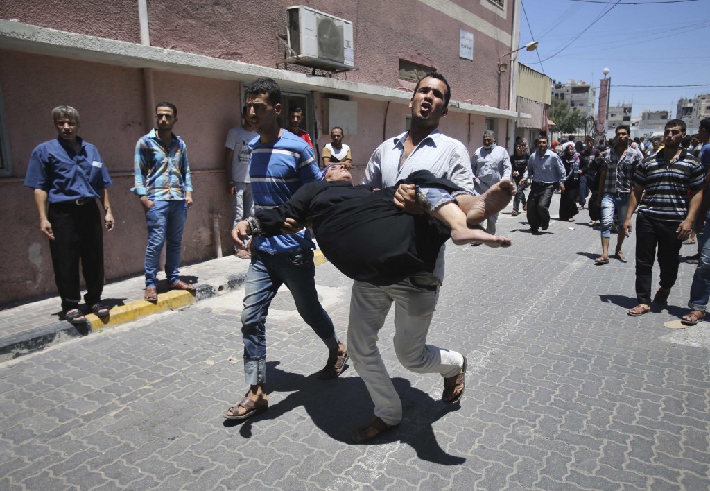 A Palestinian man rushes a woman, who medics say was wounded by an Israeli airstrike, into a hospital in Khan Younis, Gaza Strip, July 24. Fighting pushed the Palestinian death toll over 700. PHOTO: CNS/Ibraheem Abu Mustafa, Reuters