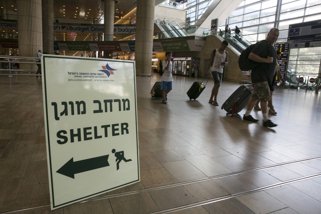 Passengers walk past a sign pointing to a shelter at Ben Gurion International Airport near Tel Aviv, Israel, July 24.  The U.S. lifted a ban on commercial flights to Tel Aviv, as fighting in the Gaza Strip continued. PHOTO: CNS/Baz Ratner, Reuters