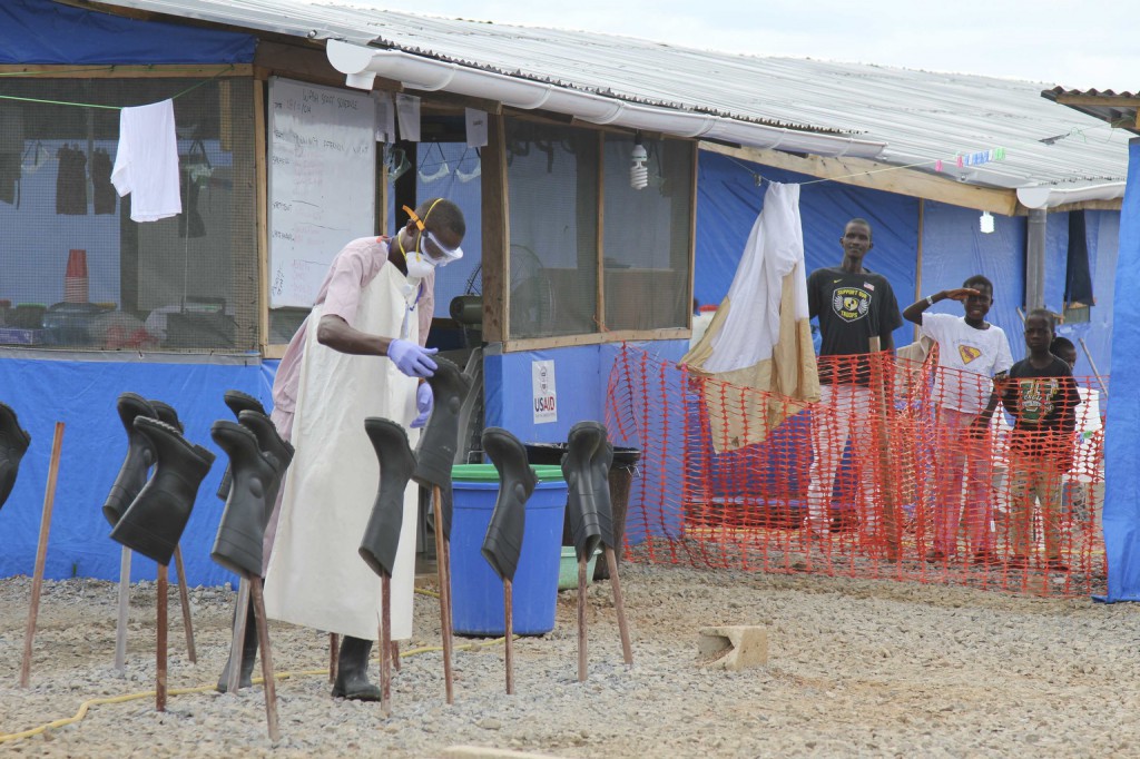 A worker disinfects boots as people look on in the "red zone" where they are being treated for Ebola at the Bong County Ebola Treatment Unit in Gbarnga, Liberia, 28 October. PHOTO: CNS/Michelle Nichols, Reuters