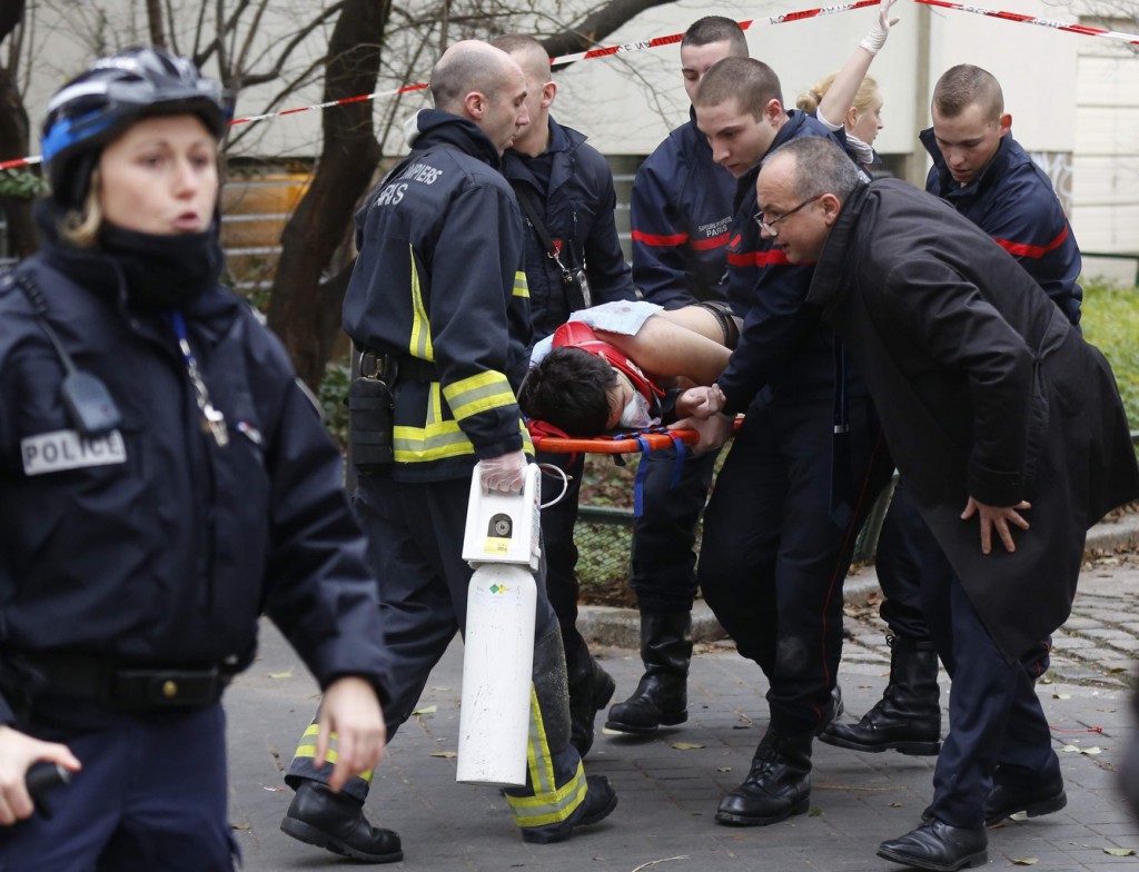 Firefighters carry a victim on a stretcher at the scene of a shooting at the Paris offices of Charlie Hebdo, a satirical newspaper, Jan. 7. photo: CNS/Jacky Naegelen, Reuters