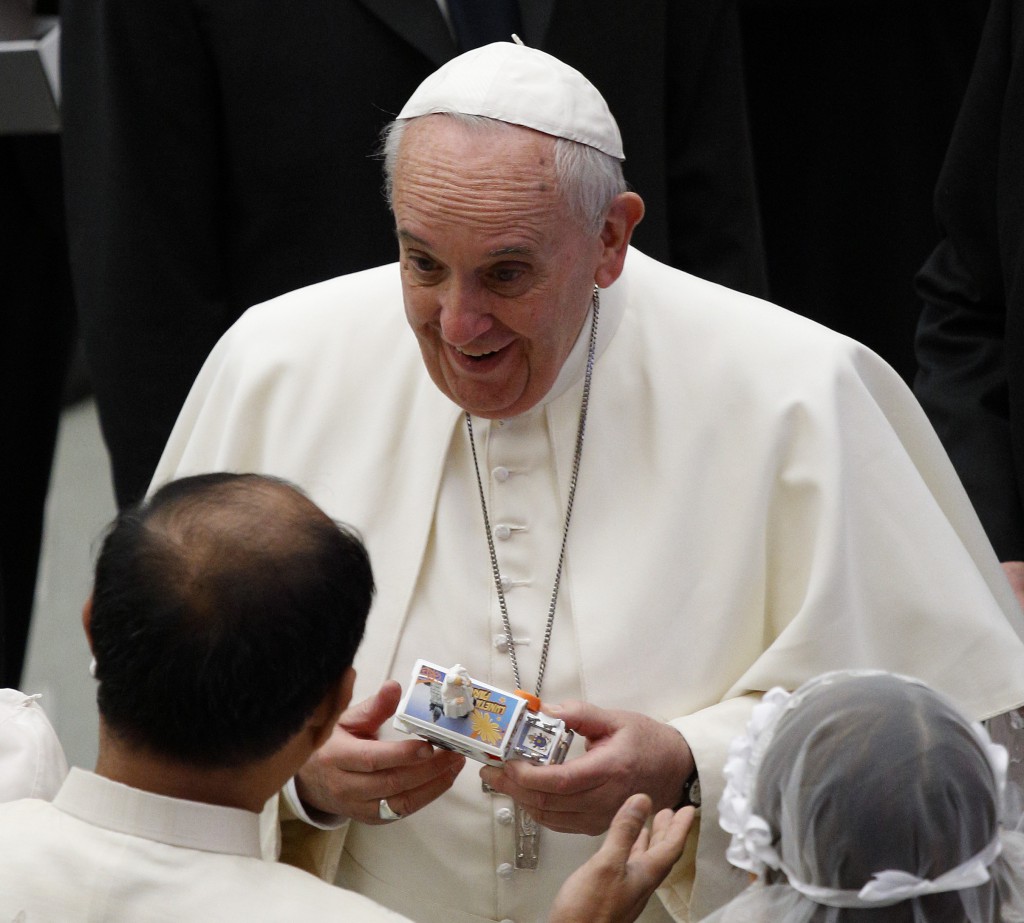 Pope Francis accepts a gift from a newly married couple during his general audience in Paul VI hall at the Vatican on 28 January. PHOTO: CNS/Paul Haring 
