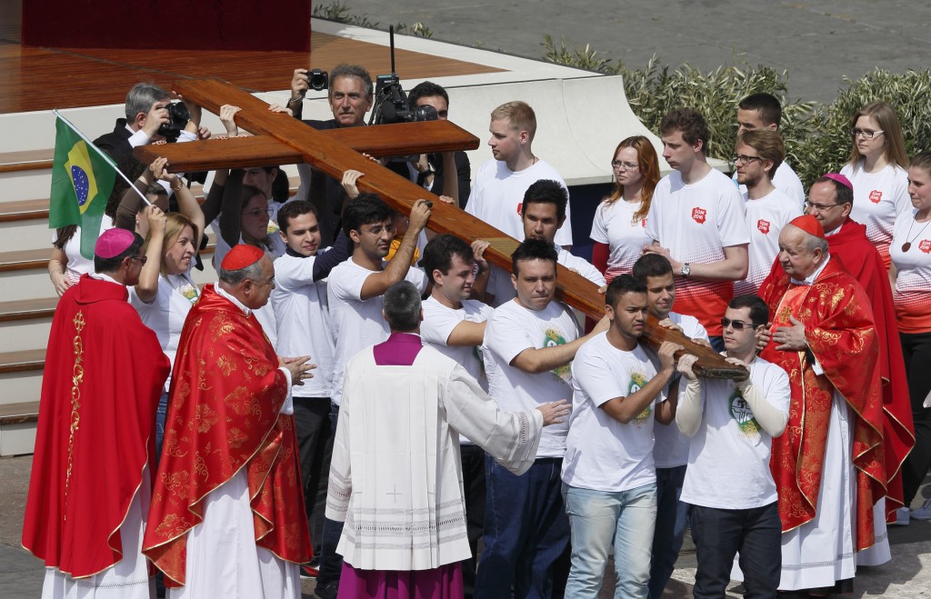 Young people from Brazil, left, pass on the World Youth Day cross to youths from Poland, right, at the conclusion of Pope Francis' celebration of Palm Sunday Mass in St. Peter's Square at the Vatican April 13. The next  international Catholic youth gathering will be July 25-Aug. 1, 2016, in Krakow, Poland. Watching at left is Brazilian Cardinal Orani Joao Tempesta of Rio de Janeiro and at right Polish Cardinal Stanislaw Dziwisz. PHOTO: CNS/Paul Haring