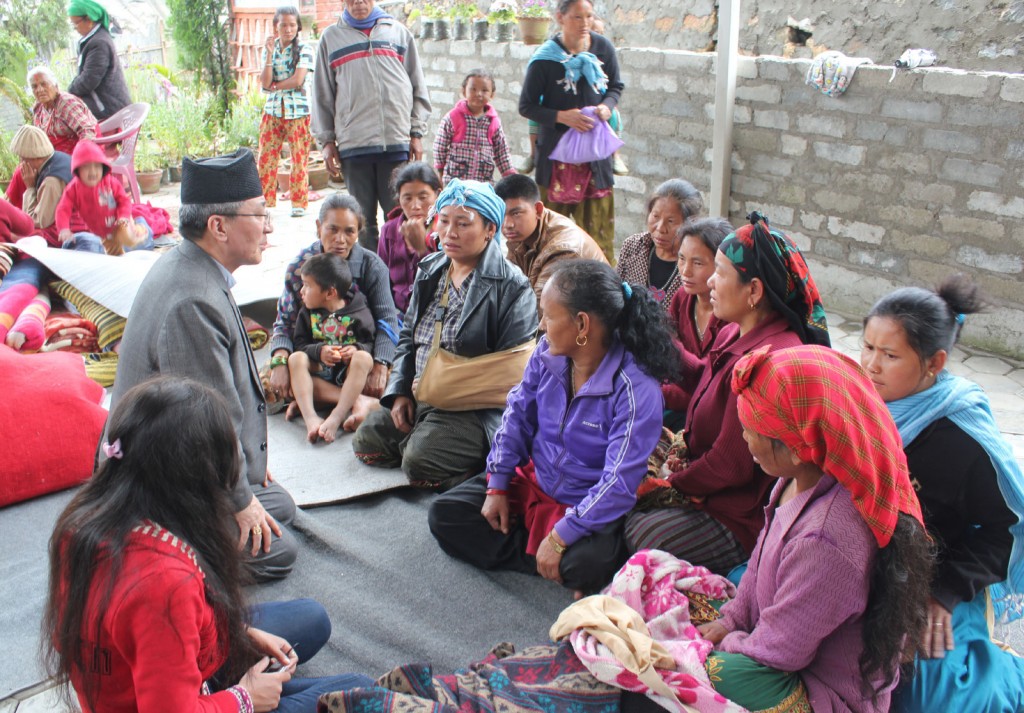 Bishop Paul Simick of Nepal talks with earthquake survivors and parishioners from St. Ignatius Church April 30 outside the church shelter near Kathmandu, Nepal. Members of 15 Catholic families have taken shelter in the church along with a dozen Hindu fam ilies following the April 25 quake. PHOTO: Anto Akkara