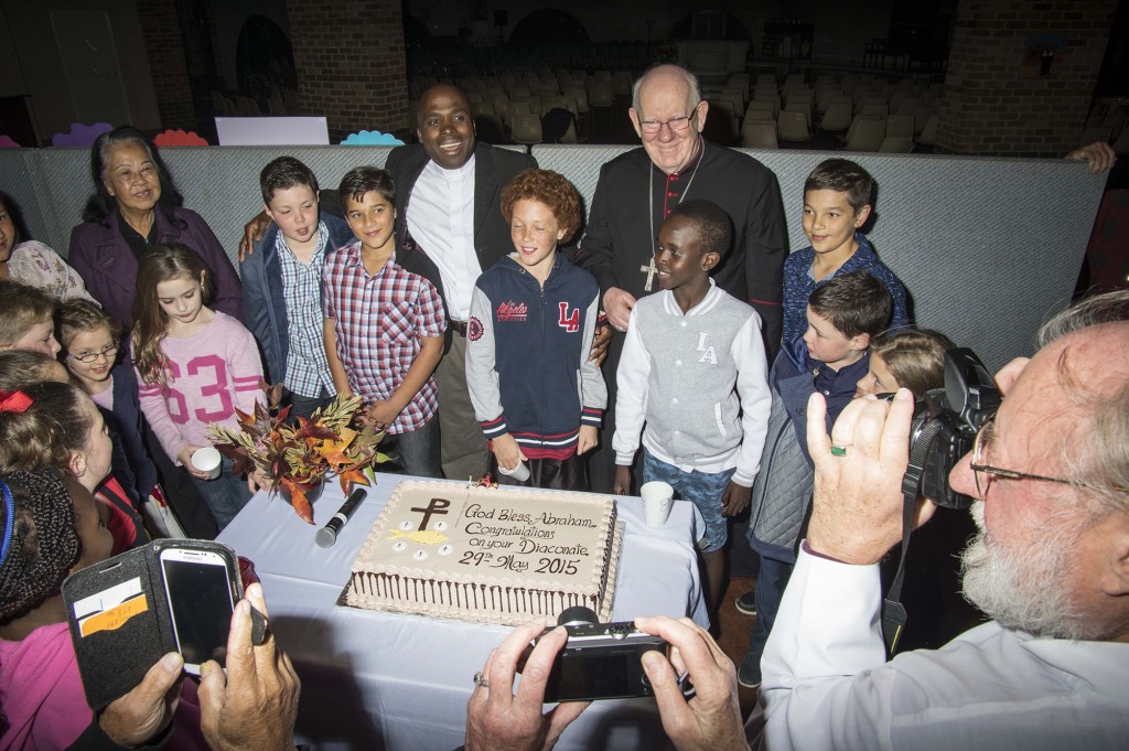 A momentous occasion: newly elected Deacon Abraham Chukwu stands besides Bunbury Bishop Gerard Holohan and parishioners from St Mary of the Cross MacKillop Catholic Church before cutting the cake for his Ordination to the Diaconate.  PHOTO: Supplied