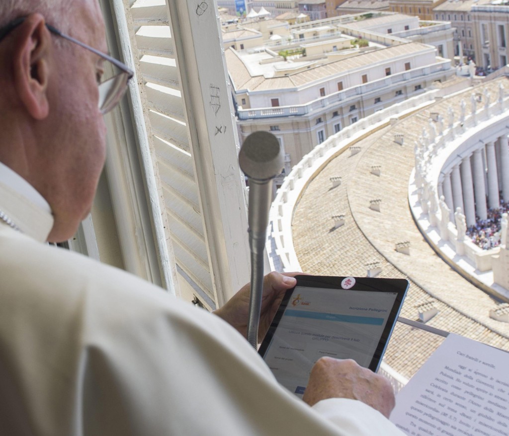Pope Francis uses a tablet to officially open online registration for World Youth Day 2016 in Poland during the Angelus at St. Peter's Square July 26. PHOTO: CNS
