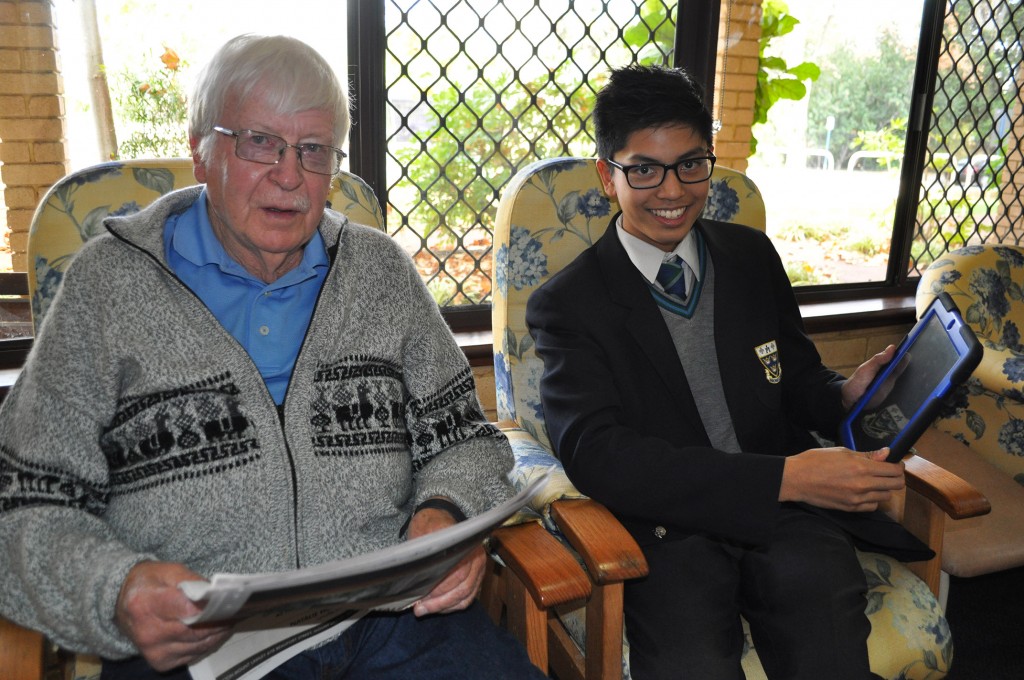 Student from Trinity College bonds over technology and the mysterious ways of the iPad with a resident at Archbishop Goody Hostel. PHOTO: Supplied