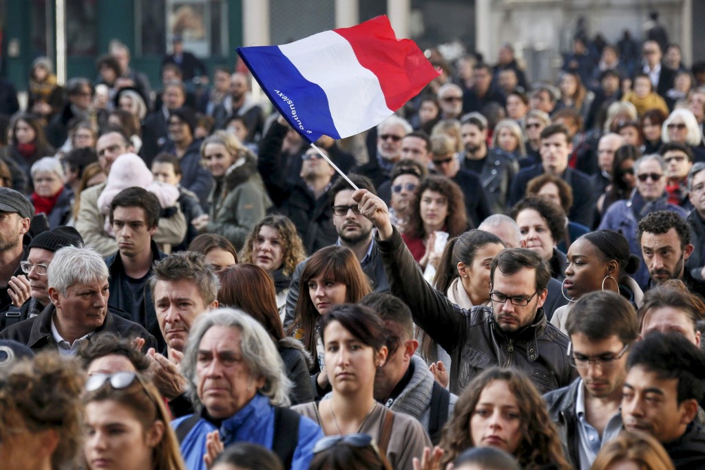 A man waves a French flag as several hundred people gather to observe a minute of silence in Lyon, France, on November 16. Photo: CNS/Robert Pratta.