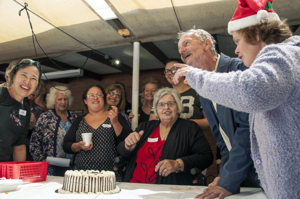 Emmanuel Centre Coordinator Barbara Harris (centre) prepares to cut the Emmanuel Centre Birthday Cake surrounded by members, friends and family of a remarkable organisation that supports people with disabilities. Photo: Marco Ceccarelli