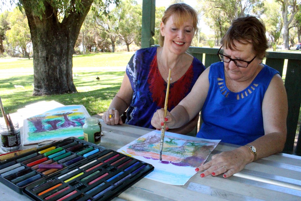 Professional artist and member of Identitywa, Wendy, oversees Adele during a painting lesson at Neil Hawkins Park in Joondalup. Photo: Supplied