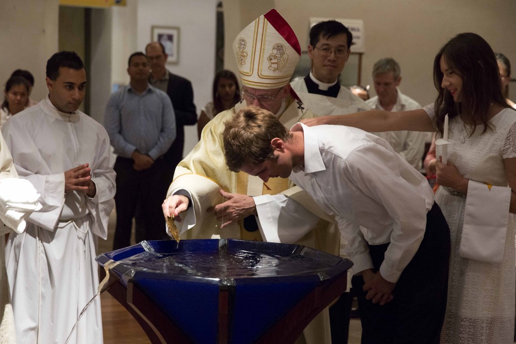 Archbishop Costelloe baptises a catechumen at the Easter Vigil on 26 March at St Mary’s Cathedral. The young man was received into the Church with 12 other catechumens and two candidates, plus another two candidates who received Confirmation. Photo: Ron Tan.