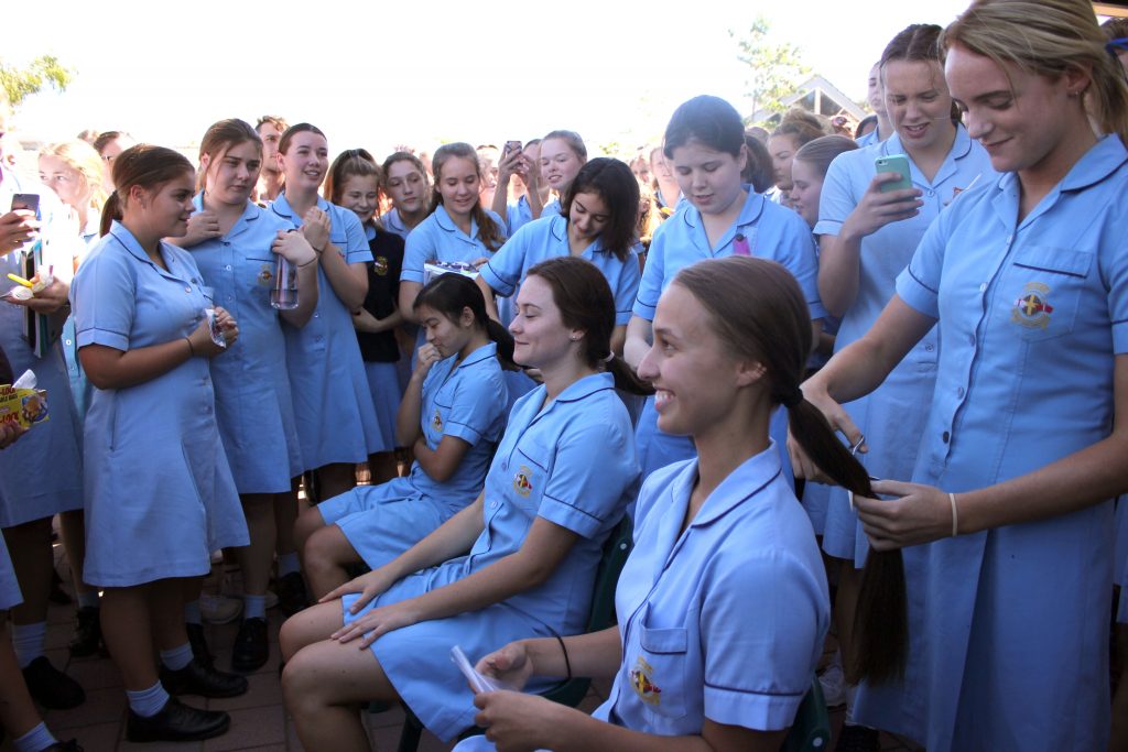 Kolbe Catholic College students prepare to cut off their hair, to be donated and made into wigs for women battling cancer, during the Chop for Cancer event. Photo: Supplied