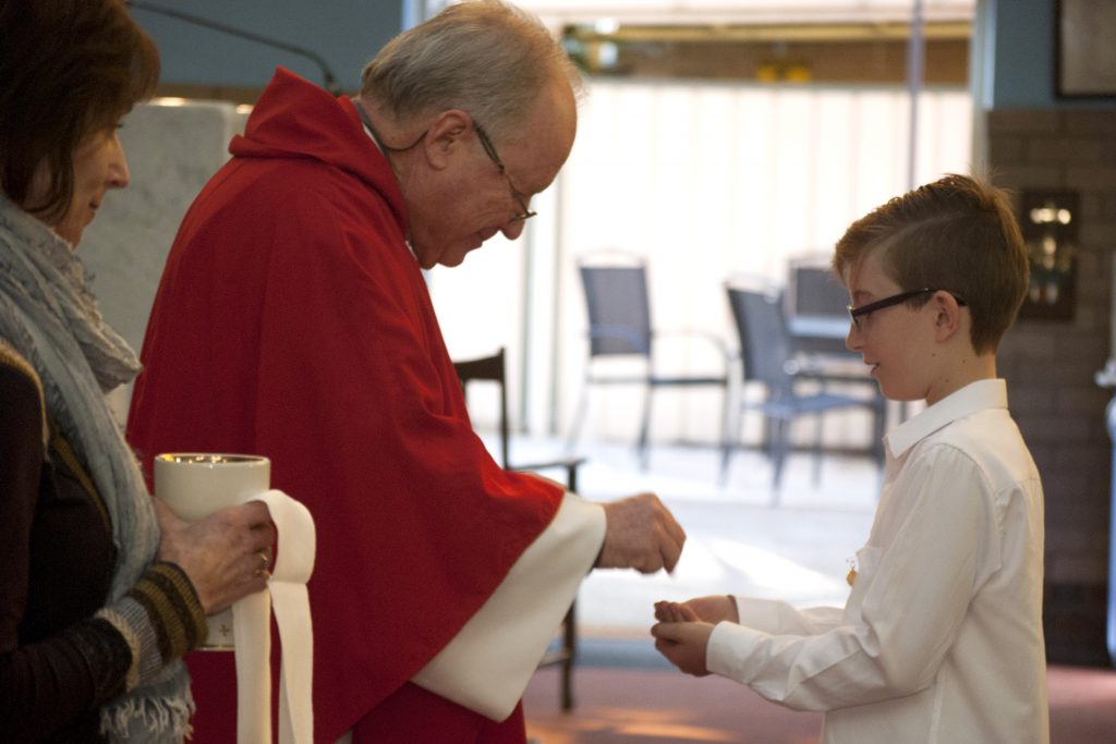 Lachlan Sofield receives the host from Fr Steve Astill SJ. Photo: Rachel Curry