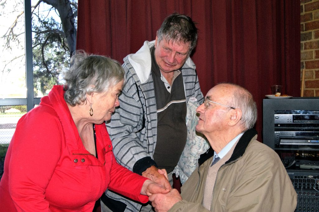 Fondness for parishioners reciprocated: Fr Joss Breen is greeted by parishioners Veronica and John Potter. Photo: Supplied