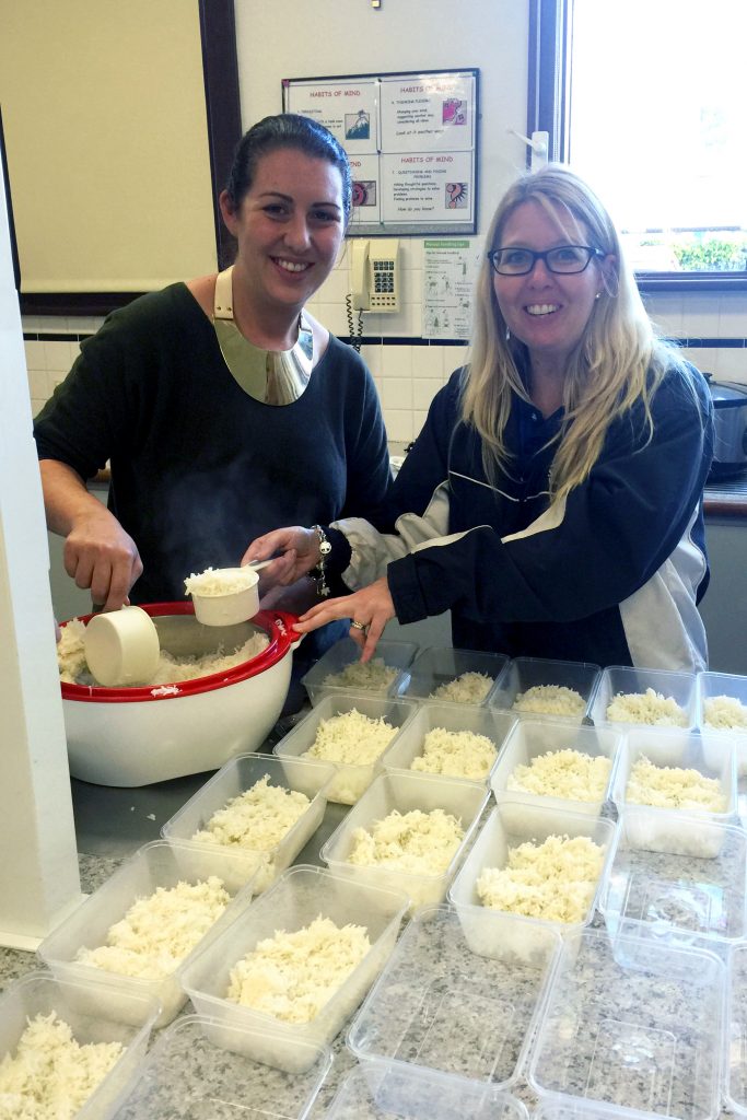 St Gerard’s Primary School staff Danielle Wardrope and Liza Britton help prepare 140 meals of chicken and vegetable casseroles and chocolate and blueberry muffins, to be served in the Perth CBD. Photo: Supplied