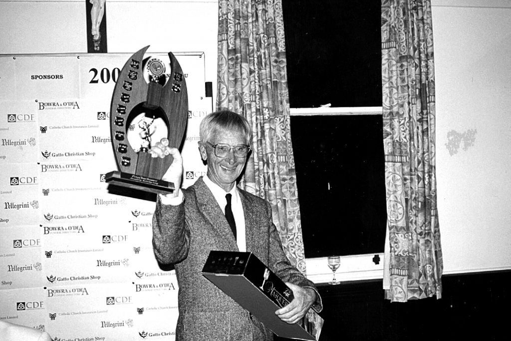 A proud and fair sportsman, Fr Peter St John holds up a trophy he won for playing his favourite sport: tennis. Photo: Supplied