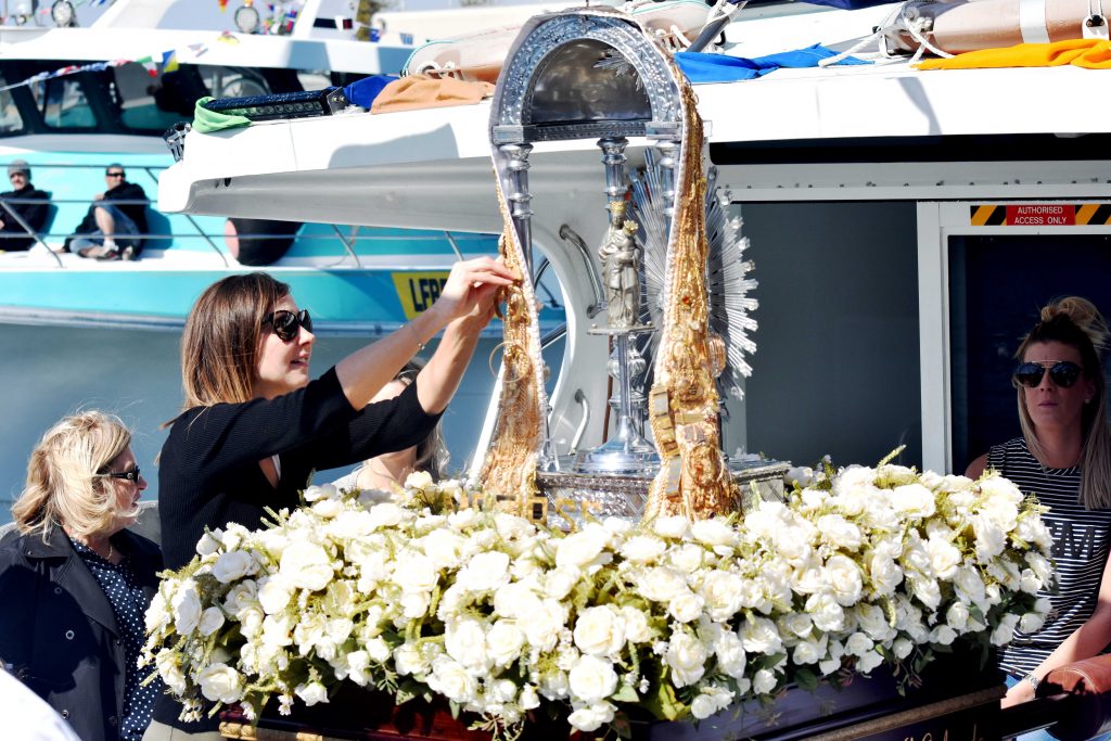 A young woman pins a donation to the statue of La Madonna di Capo d’Orlando. Photo: Daniele Foti-Cuzzola