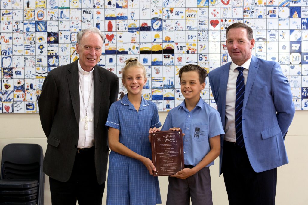 Archdiocese of Perth Auxiliary Bishop Don Sproxton poses with Infant Jesus School students Antonia Holub and Tyrone Virgo and Principal Paul Hille, after presenting the school with the 2015 Archbishop’s Spirit Award. Photo: Ron Tan