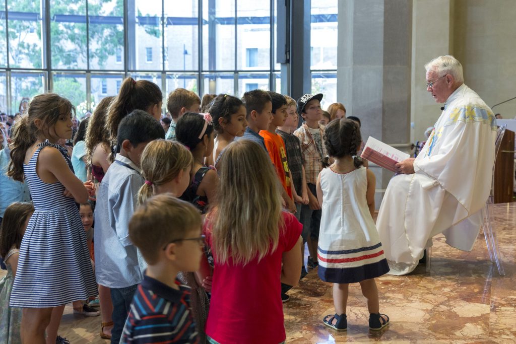 Dean of St Mary’s Cathedral Monsignor Michael Keating reads to young worshippers during the Children’s Mass on Christmas Day. Photo: Ron Tan