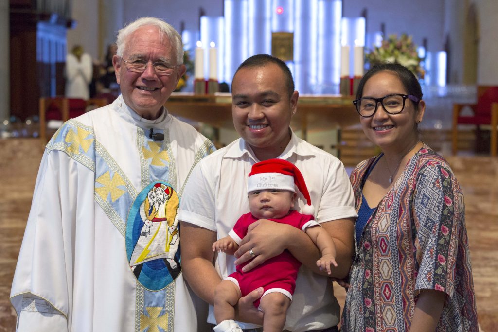Dean of St Mary’s Cathedral Monsignor Michael Keating pictured with Ralph and Luanne Alegre and their son Liam Antonio, who was the Infant Jesus during the Children’s Mass. Photo: Ron Tan