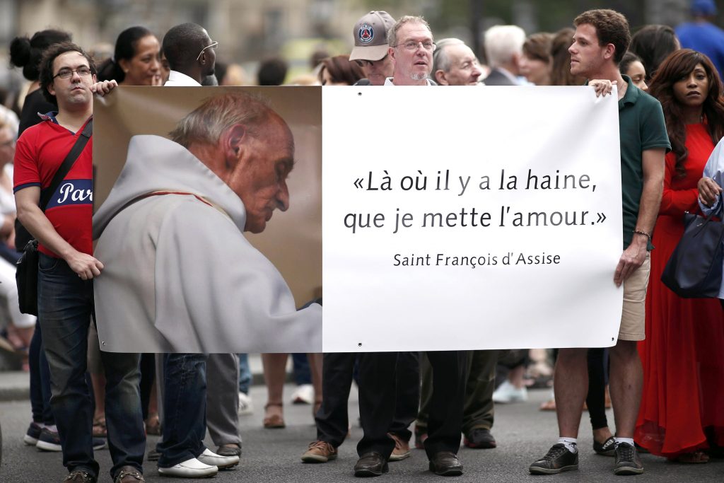 People hold a banner with a picture of French priest Father Jacques Hamel, which reads, "Where there is hatred, let me sow love," after a 27 July Mass at the Notre Dame Cathedral in Paris. Father Jacques Hamel was killed in a 26 July attack on a Church at Saint-Etienne-du-Rouvray near Rouen by assailants linked to Islamic State groups. Photo: CNS/Benoit Tessier, Reuters