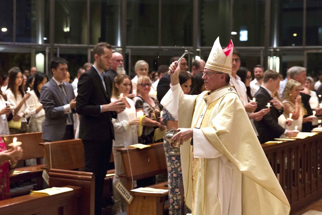 Archbishop Timothy Costelloe sprinkles holy water on the congregation during the Easter Vigil celebration at St Mary’s Cathedral on Saturday 15 April. Photo: Ron Tan