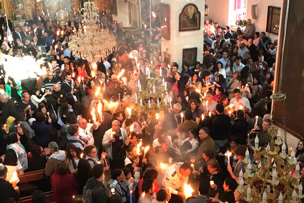 Pilgrims spreading the Holy Fire via candles in the Orthodox Church. Photo: Gemma Thomson