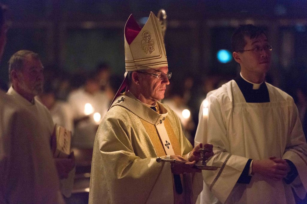 Archbishop Timothy Costelloe holds a candle during the celebration of the Easter Vigil at Mary’s Cathedral on Saturday 15 April. Photo: Ron Tan
