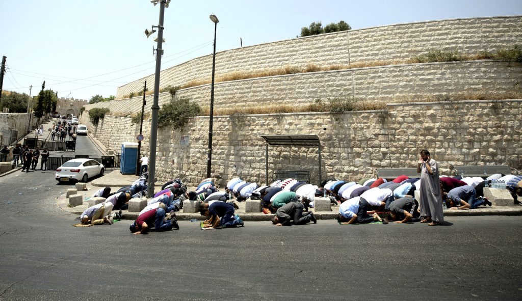 Palestinians pray on the street close to Lion's Gate in the Old City of Jerusalem on July 22. Muslims have been converging outside the gate for prayers after Israel erected metal detectors near the Al-Aqsa mosque compound, in response to a July 14 shooting. Photo:CNS/Atef Safati, EPA.