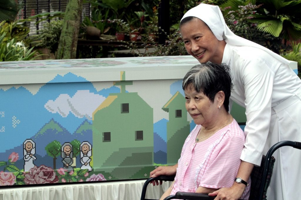 Canossian Sister Geraldine Tan, administrator of St Joseph's Home and Hospice, smiles as she pushes a patient in her wheelchair in 2010 outside the facility in Singapore. Photo: CNS/Stephen Morrison, EPA.