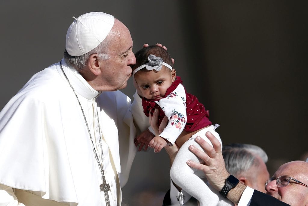Pope Francis kisses a baby during his general audience in St Peter's Square at the Vatican on 7 November. Photo: Paul Haring/CNS.