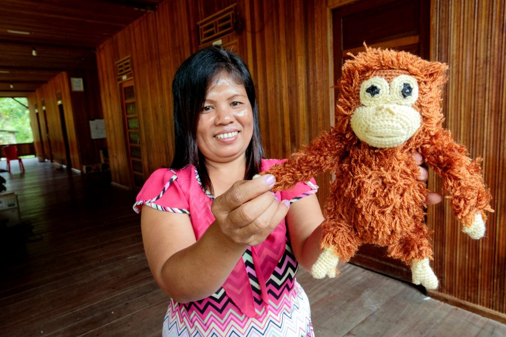 Tati on the veranda of the eco-tourism project long house showing a woollen orangutan doll she made to sell to tourists. Photo: Richard Wainwright/Caritas Australia.