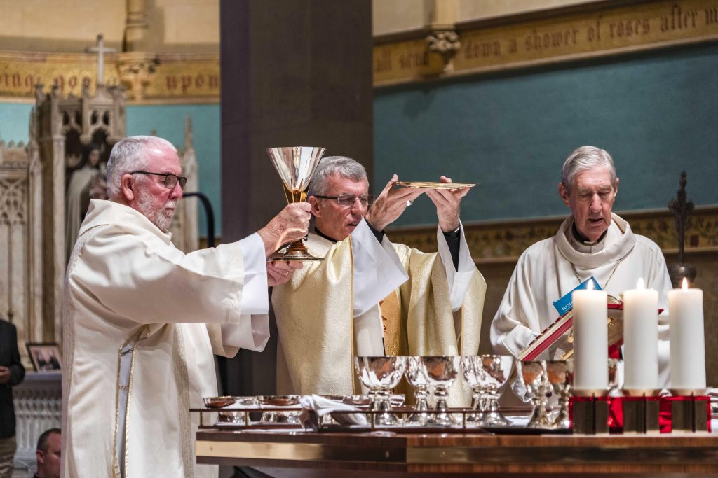 Archbishop Costelloe during the concluding doxology of the Eucharistic Prayer, assisted by Deacon Patrick Moore. Photo: Josh Low.