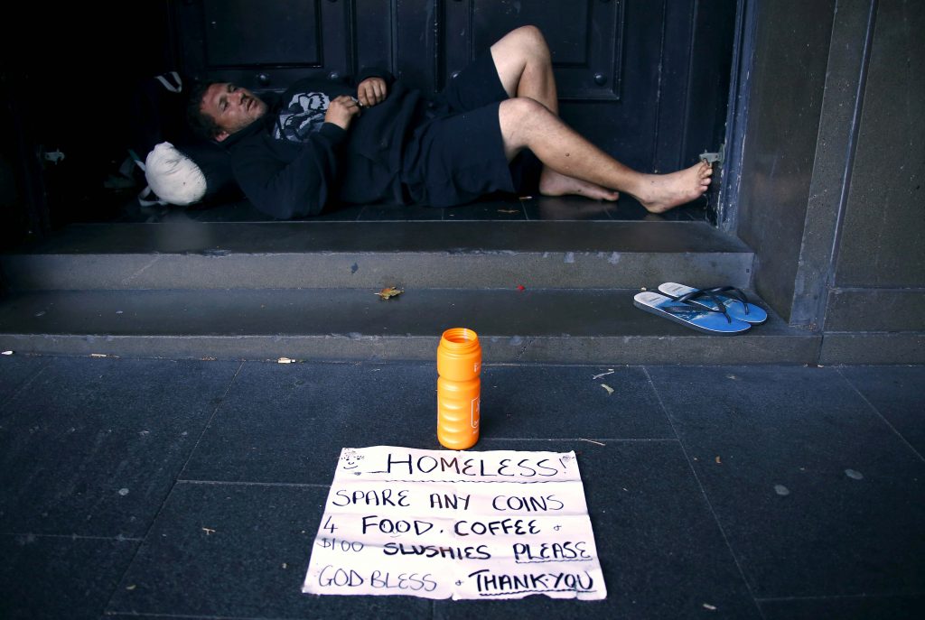 A man rests in the doorway of a building. Photo: David Gray, Reuters.
