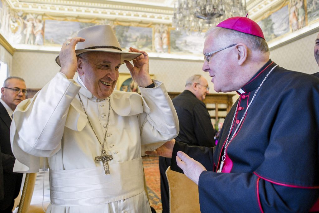 Pope Francis tries on a hat presented by Archbishop Mark Coleridge, during a meeting with Australian bishops on their Ad Limina visit to the Vatican on 24 June 2019. Photo: CNS /Vatican Media.