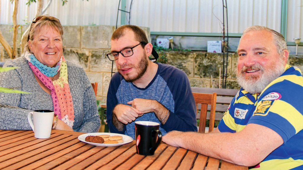 Since 2017, 29-year-old Alex has been living in one of Identitywa’s shared houses, supported by the NDIS. Alex is in the photo with his parents. Photo: Identitywa.