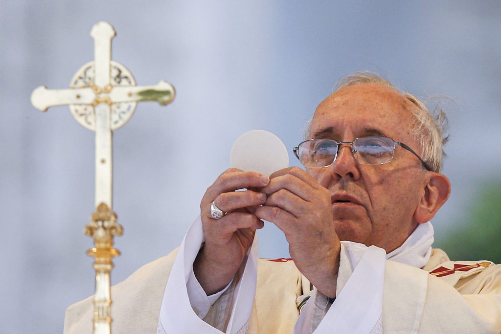 In this 2014 file photo, Pope Francis elevates the Eucharist as he celebrates Mass on the feast of Corpus Christi outside the Basilica of St John Lateran in Rome. Photo: Paul Haring/CNS.