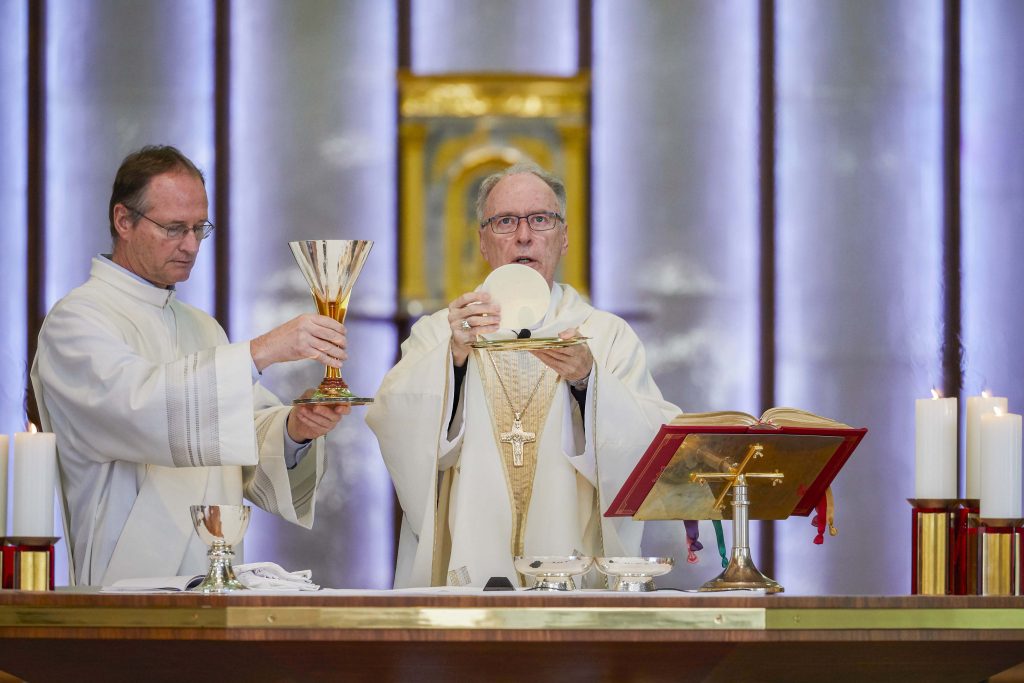 Auxiliary Bishop of Perth Donald Sproxton elevates the Eucharist as Deacon Gregory Lowe holds the chalice during the Archdiocesan Agencies Mass at St Mary’s Cathedral on 23 July 2019. Photo: Ron Tan.