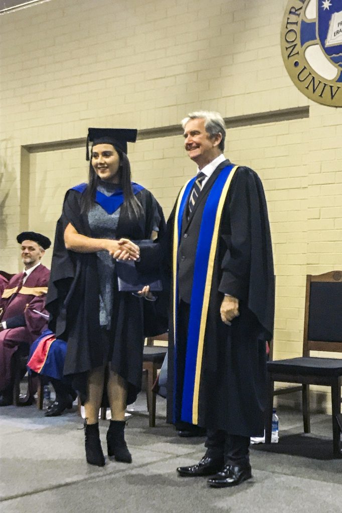 Catenian Scholarship recipient Ashleigh Habkouk and UNDA Chancellor Christopher Ellison pose for photographers at Ms Habkouk’s graduation ceremony, where she delivered the valedictory speech. Photo: Supplied.