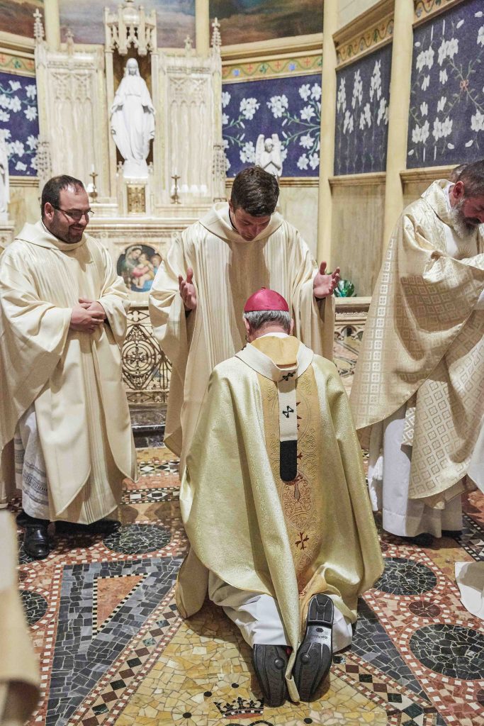Archbishop Costelloe receives a blessing from newly ordained priest Fr Liam Ryan. Photo: Ron Tan.