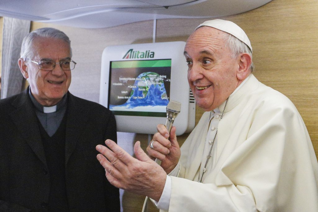 Jesuit Father Federico Lombardi, looks on as Pope Francis talks to journalists in 2015 aboard his flight from Rome to Nairobi, Kenya. The retired papal spokesman says Pope Francis' communications style differs from Pope Benedict's but both papacies reflect continuity based on pontiffs' understanding of the church. Photo: CNS/Paul Haring.