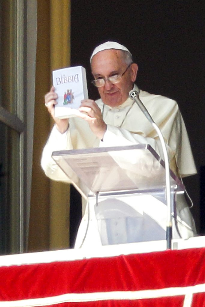 Pope Francis holds up a Bible as he promotes reading of the Bible during his Angelus delivered from the window of his studio overlooking St Peter's Square at the Vatican on 5 October 2014. Photo: Paul Haring/CNS.
