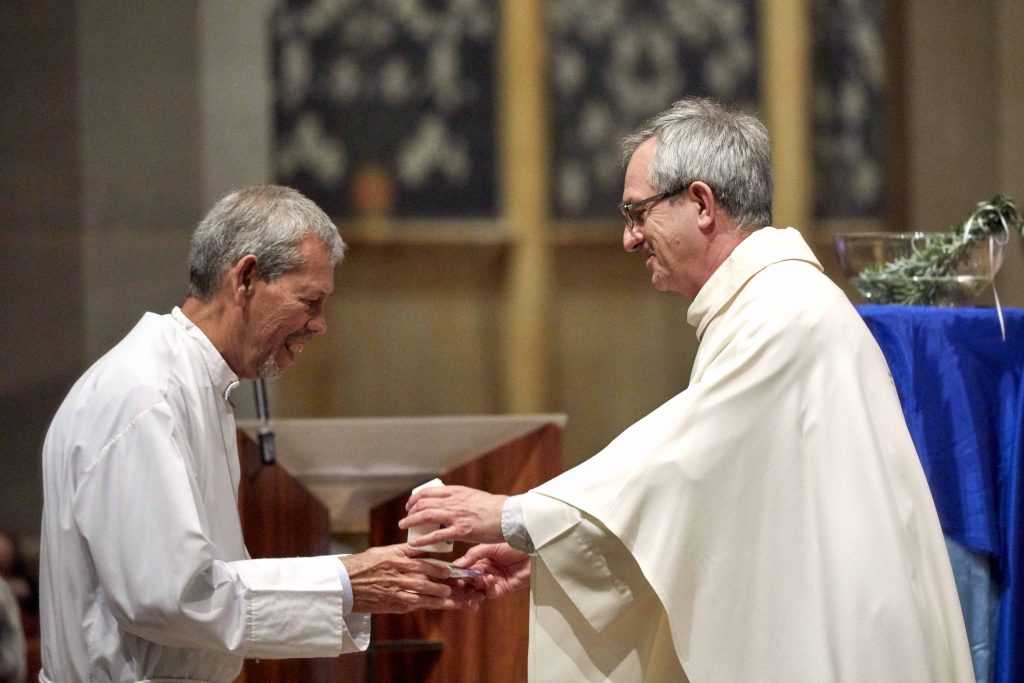 SVDP Chaplain Fr Nino Vinciguerra presents a memorial candle to one of the Society’s Regional Presidents. Photo: Ron Tan.
