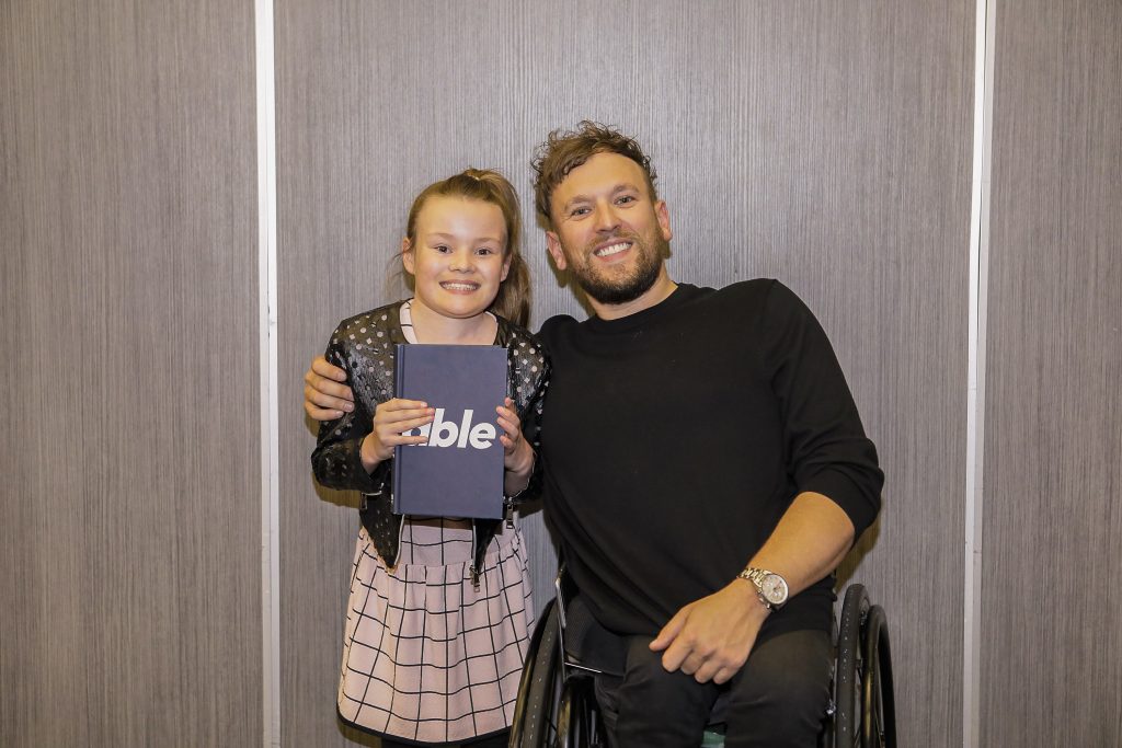 Guest Madi with Dylan Alcott OAM at the MercyCare Oration 2019 at the Perth Convention and Exhibition Centre on September 23. Madi is holding Dylan’s book titled Able. Photo: MercyCare.